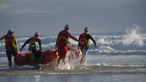 Salvavidas-Voluntarios-Llevando-Un-Bote-Inflable-De-Goma-En-El-Océano---Socorristas-De-Servicio-Y-Preparándose-Para-Patrullar---Currumbin,-Gold-Coast,-Queensland,-Australia