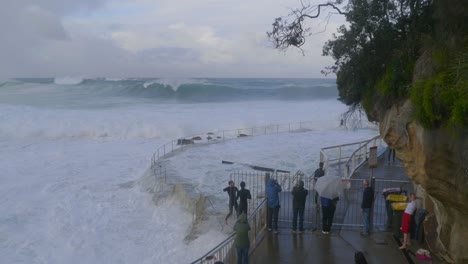 Young-Men-Cross-Over-The-Railings-And-Go-To-The-Dangerous-Waves-In-Bronte-Beach---Storm-In-Sydney,-Australia---high-angle-shot