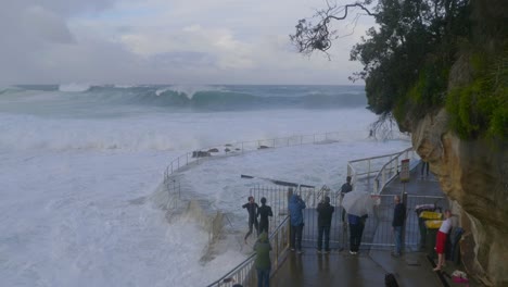 Junge-Männer-überqueren-Das-Geländer-Und-Gehen-Zu-Den-Gefährlichen-Wellen-Am-Bronte-Beach-–-Sturm-In-Sydney,-Australien-–-Aufnahme-Aus-Der-Vogelperspektive