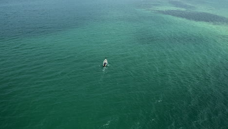 drone-following-longtail-boat-driving-on-ocean-with-small-waves,-aerial