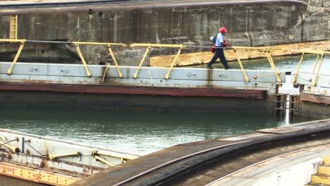 Hombre-Caminando-Sobre-Las-Puertas-Cerradas-De-La-Cámara-En-Las-Esclusas-De-Gatun,-Canal-De-Panamá