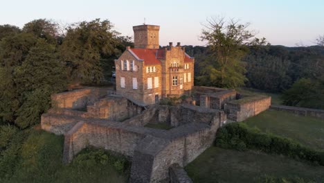 Nahe-Luftdrohnenumlaufbahn-Der-Restaurierten-Mittelalterlichen-Burg-Auf-Einem-Bergrücken,-Der-Von-Der-Goldenen-Morgendämmerung-Beleuchtet-Wird