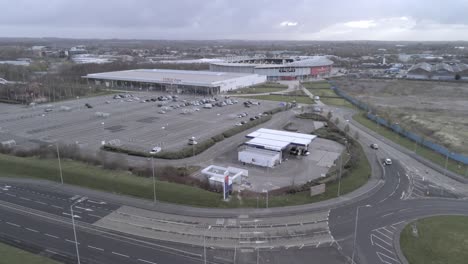 Corona-virus-lockdown-town-empty-retail-area-shopping-aerial-view-rising-above-car-park-traffic-below