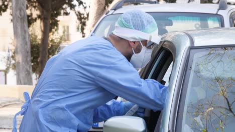 Un-Trabajador-Médico-Realiza-Una-Prueba-De-Hisopo-De-Coronavirus-En-Una-Persona-En-Su-Automóvil-En-La-Ciudad-De-Pafos,-Chipre,-Grecia,-Durante-La-Pandemia-De-Covid-19