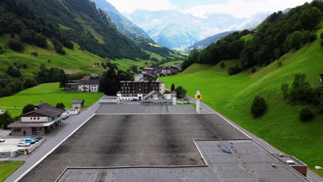 Aerial-shot-flying-backwards-and-down-revealing-Elmer-mineral-water-plant-in-Elm,-Glarus,-Switzerland