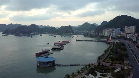 Lan-Ha-Bay-in-the-south-of-the-Island-as-the-sun-sets,-floating-restaurants-adorn-Hung-Long-Harbor,-Aerial-flyover-shot