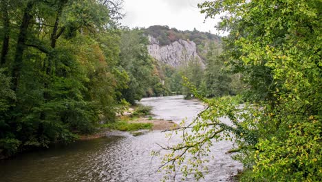 River-in-woods-time-lapse,-horse-riders-passing,-castle-in-background