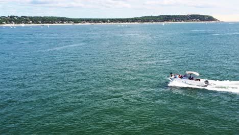 Motorboat-with-people-on-Arcachon-Bay-near-Dune-du-Pilat-sand-dune,-Aerial-orbit-around-shot