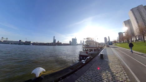 Toma-De-Retroceso-Del-Nuevo-Río-Mosa-En-Rotterdam,-Países-Bajos,-Con-Vista-Lejana-Del-Puente-Erasmus-Desde-El-Paseo-Marítimo---Hiperlapso