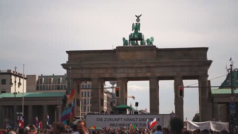 Manifestantes-En-Cámara-Lenta-En-Una-Manifestación-De-Covid-19-Corona-Contra-El-Uso-De-Máscaras-Faciales-Contra-La-Pandemia-En-La-Capital-De-Alemania,-Berlín,-Sosteniendo-Carteles-Y-Acercándose-A-La-Puerta-De-Brandenburgo