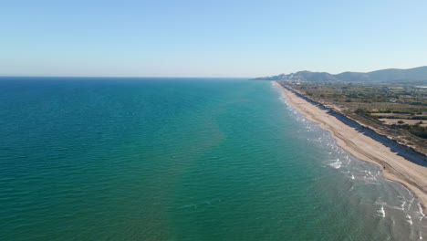 Aerial-side-view-of-long-sandy-beach-on-the-Mediterranean-coast-in-Valencia,-Spain