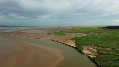 Wide-aerial-view-of-a-costal-bay-at-low-tide,-showing-the-natural-pattens-left-behind,-bright-day