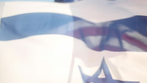 Die-Flagge-Israels-Weht-In-Zeitlupe,-Im-Hintergrund-Lauert-Die-Amerikanische-Flagge,-Zeitlupe