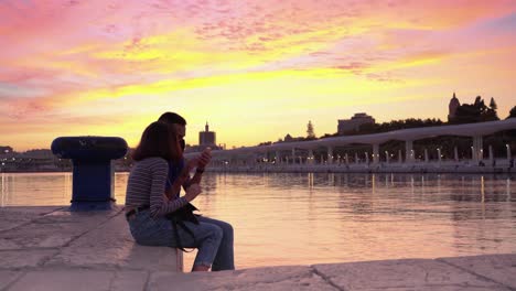 A-Couple-Enjoy-Romantic-Evening-at-Waterfront-Watching-Vivid-Colorful-Sunset