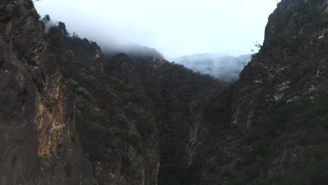 Aerial-drone-flying-close-to-the-top-of-a-huge-canyon-above-a-gorge-covered-in-thick-bush-land-on-a-foggy-morning-in-the-Bungonia-National-Park-NSW-Australia