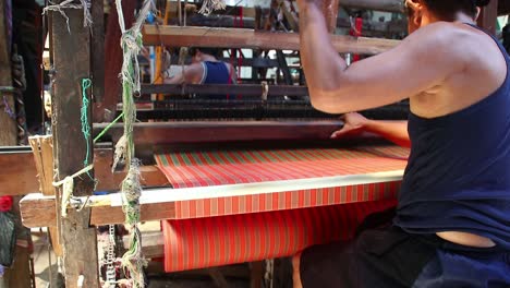 workers-weaving-thread-into-cloth-using-traditional-looms,-low-light-video-in-a-dark-room,-Pekalongan