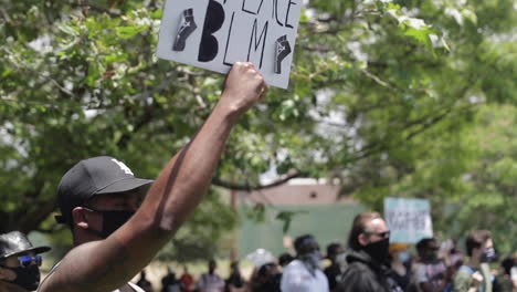 „Black-Lives-Matter“-Demonstrant-Hält-Bei-Einer-Kundgebung-Ein-Schild-Hoch,-Schwenk-In-Zeitlupe-Zum-Gesicht