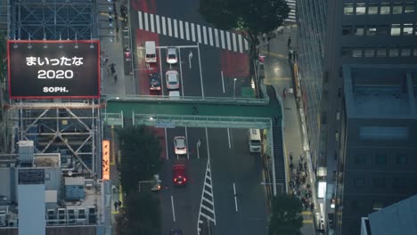 ángulo-Alto-De-Arriba-Hacia-Abajo-Toma-Larga-De-Peatones-Y-Tráfico-Por-La-Noche-En-Shibuya,-En-Tiempo-Real