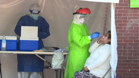 female-doctor-wearing-full-anticovid-suit-while-conducting-a-covid-test-on-a-patient