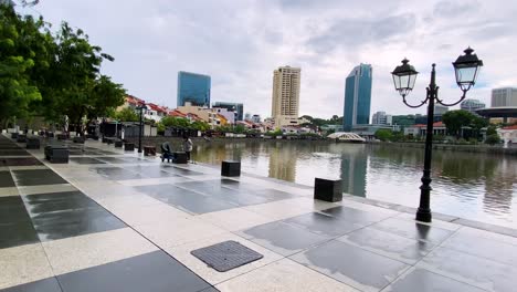 Trabajador-Recogiendo-Basura-En-Un-Espacio-Vacío-Frente-A-La-Plaza-Del-United-Foreign-Bank-Frente-Al-Río-Singapur-Durante-La-Pandemia---Plano-Amplio