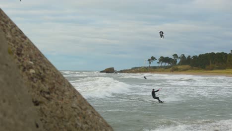 Eine-Gruppe-Von-Leuten,-Die-An-Einem-Sonnigen-Herbsttag-Kitesurfen-Betreiben,-Akrobatische-Sprünge,-Hohe-Wellen,-Ostsee-Karosta-Strand-In-Liepaja,-Weitwinkelaufnahme