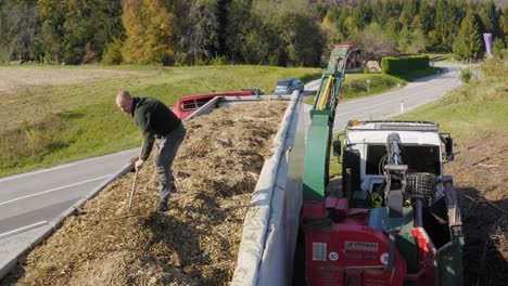 Erwachsener-Arbeiter-Harkt-Hackschnitzel-Auf-Dem-Dach-Eines-Lastwagens