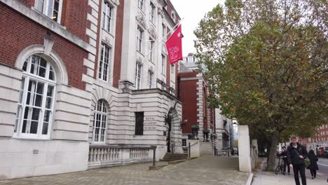 Flag-flying-over-entrance-to-Royal-Academy-of-music-people-walking-in-street