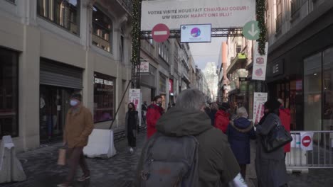 Walking-to-the-entrance-of-Belgian-shopping-street-Rue-Neuve-in-Brussels,-Belgium,-where-masked-security-people-provide-each-individual-with-anti-bacterial-disinfectant-spray