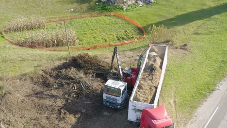 A-drone-shot-of-tree-chipper-machine-grinding-tree-into-a-covered-truck