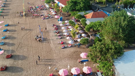 Paso-Elevado-Aéreo-Hermosa-Playa-De-Legian-Con-Sombrillas-Y-Turistas-Durante-El-Día-Soleado