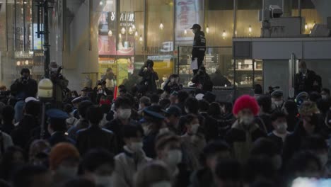 Photographers-Taking-Pictures-Of-The-Crowd-Scrambling-At-Shibuya-Crossing-On-Halloween-Night-With-Policemen-On-Guard---static-shot,-slow-motion