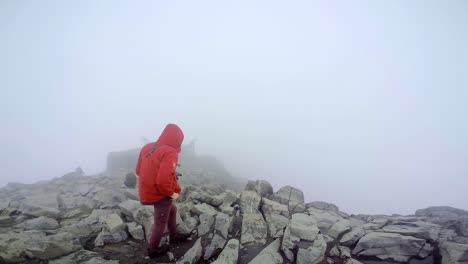 Gruppe-Von-Bergsteigern-Steht-Auf-Dem-Felsigen-Gipfel-Des-Galdhopiggen-Mit-Fallendem-Schnee-Und-Nebel-–-Dem-Höchsten-Berg-Norwegens,-Skandinaviens-Und-Nordeuropas