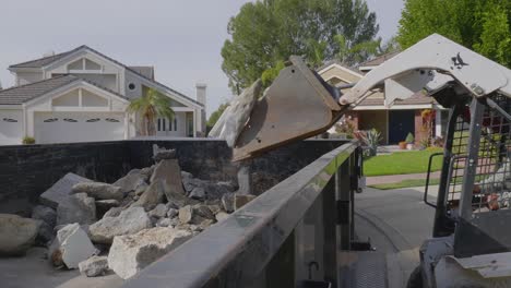 worker-dumping-busted-concrete-into-trailer-using-a-mini-Bobcat