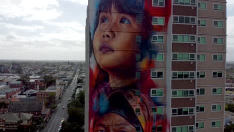 Toma-De-Drone-De-Un-Hermoso-Mural-De-Una-Torre-En-Melbourne,-Australia,-Que-Representa-La-Diversidad-De-Residentes-Y-Migrantes-Que-Viven-En-El-País.