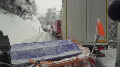 Schneepflug-Steht-Hinter-Lastwagen,-Die-Auf-Verschneiter,-Vereister-Straße-Stecken-Bleiben