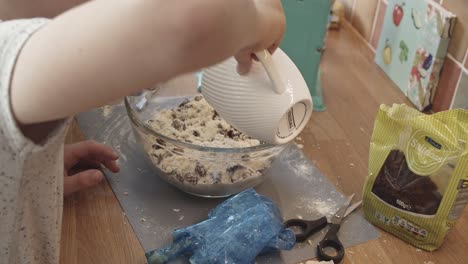 Child-helps-grandmother-to-prepare-cake-with-raisins