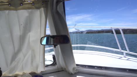 Boat-Tour---Adult-Indigenous-Man-Driving-Wooden-Motorboat-Across-Lake-Titicaca-On-A-Sunny-Day-In-Peru