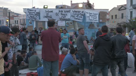 Crowd-of-refugees-protest-in-Sappho-Square,-Mytilene-following-death-of-Afghan-man,-WIDE-SHOT