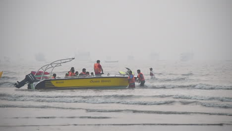A-group-of-tourists-reached-near-a-shore-on-beach-after-a-water-sports-ride-in-speed-boat-in-sea-on-beach-in-Mumbai-city-and-preparing-for-departure-from-boat-,-India-video-background-in-Pro-res