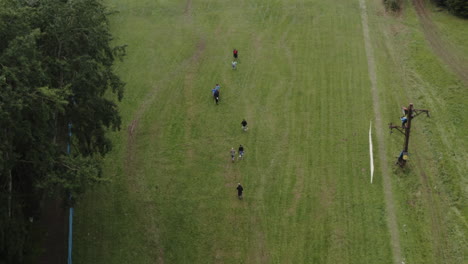 Luftaufnahme-Von-Menschen,-Die-Auf-Einem-Hügel-Spazieren-Gehen,-Um-Sich-Den-Ski-Abfahrtswettkampf-Auf-Gras-Anzusehen,-Sportpublikum