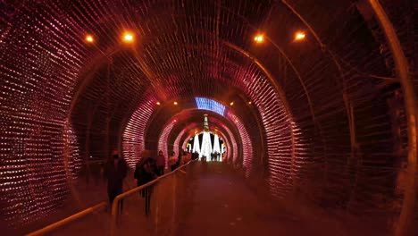 Menschen-Mit-Gesichtsmaske,-Die-Während-Der-Weihnachtszeit-In-Funchal-Inmitten-Einer-Pandemie-Auf-Madeira,-Portugal,-In-Den-Tunnel-Mit-Stroboskoplicht-Gehen,-Der-Nachts-Blinkt