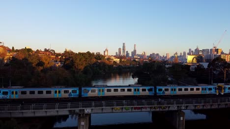Drone-of-the-sweeping-Melbourne-skyline-as-a-train-passes-by---Australia