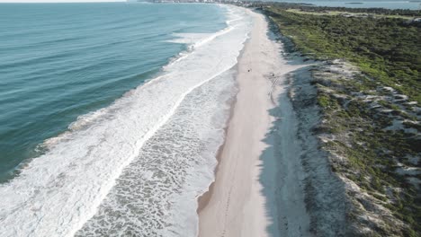 Moving-drone-shot-of-Magenta-Beach-as-the-waves-crash-along-the-shore