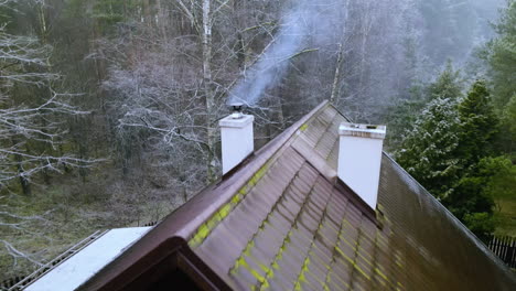 Aerial-Slow-drone-back-movement-showing-red-tiled-roof-and-white-smoke-from-chimneys-of-the-old-traditional-polish-house-in-Bartoszylas-village-in-January