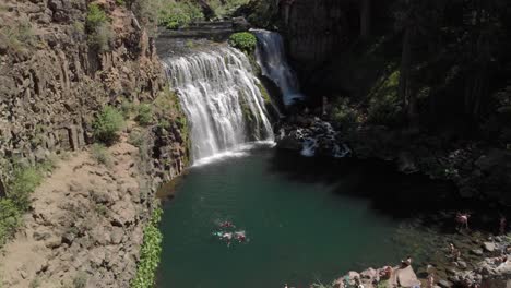 Vista-Aérea-De-Proximidad-Revela-Nadadores-En-Una-Piscina-Verde-Debajo-De-McCloud-Falls