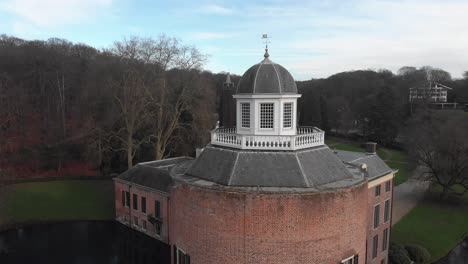 Panorámica-Aérea-Alrededor-Del-Faro-En-La-Parte-Superior-De-La-Torre-Del-Castillo-Rosendael-Con-Foso-Y-Jardín-De-Invierno-Y-Estanque-Al-Fondo.