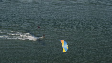 A-dynamic-tracking-aerial-footage-of-kitesurfers-giving-into-the-wind-going-steady-while-the-other-one-changes-direction-and-jumps-into-the-air-doing-a-back-flip-to-avoid-contact-against-the-other-one