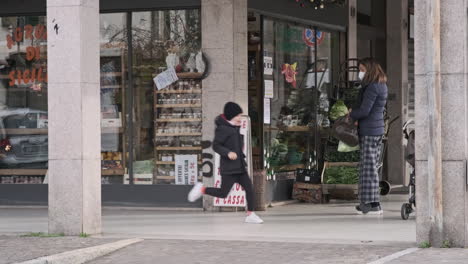 Eine-Frau-Trägt-Eine-Medizinische-Maske,-Während-Sie-Vor-Dem-Markt-In-Der-Stadt-Wartet