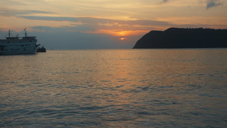Blick-Auf-Das-Meer-Bei-Sonnenuntergang-Mit-Boot-Und-Insel-Am-Horizont