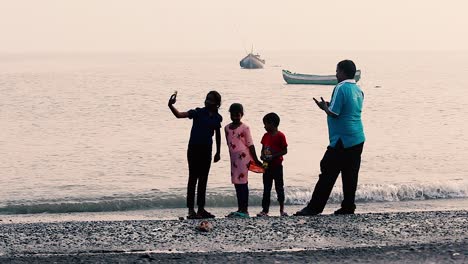 A-Indian-young-siblings-taking-selfie-with-the-phone-camera-and-a-father-is-clicking-pictures-of-kids-near-a-beach-shore